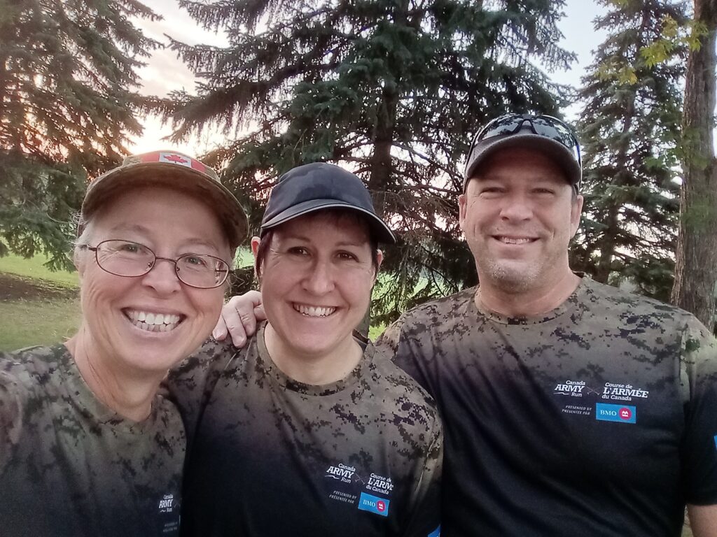 Three smiling people wear Canada Army Run shirts. | Trois personnes souriantes portent des chandails de la Course de l'Armée du Canada.