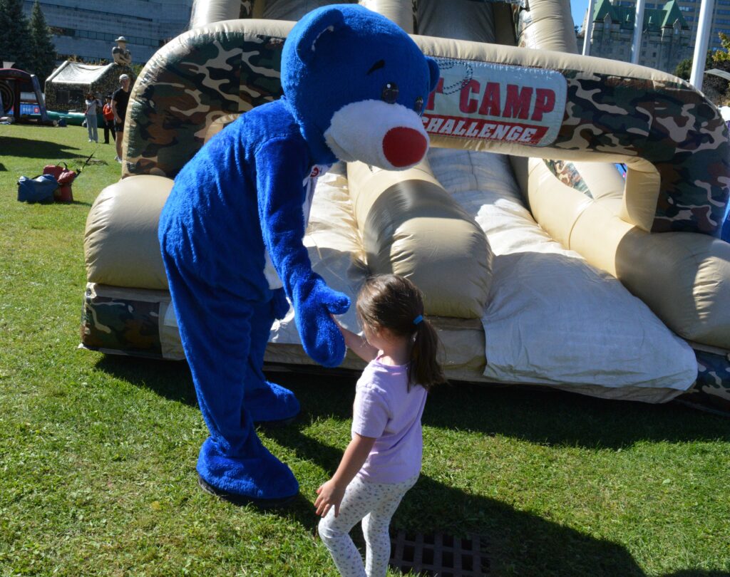 The BMO Bear high fives a young girl after the obstacle course. | L'ours BMO tape dans la main d'une petite fille à la fin du parcours d'obstacles.
