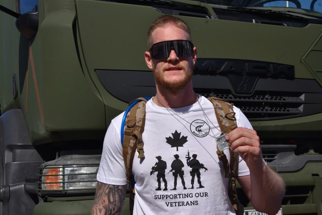 A man holds up his Canada Army Run medal. | Un homme brandit sa médaille de la Course de l'Armée du Canada.