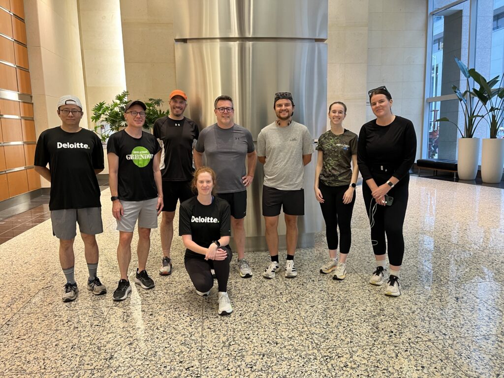 A group of runners poses inside an office building. | Un groupe de coureurs pose à l'intérieur d'un immeuble de bureaux.