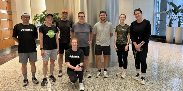 A group of runners poses inside an office building. | Un groupe de coureurs pose à l'intérieur d'un immeuble de bureaux.