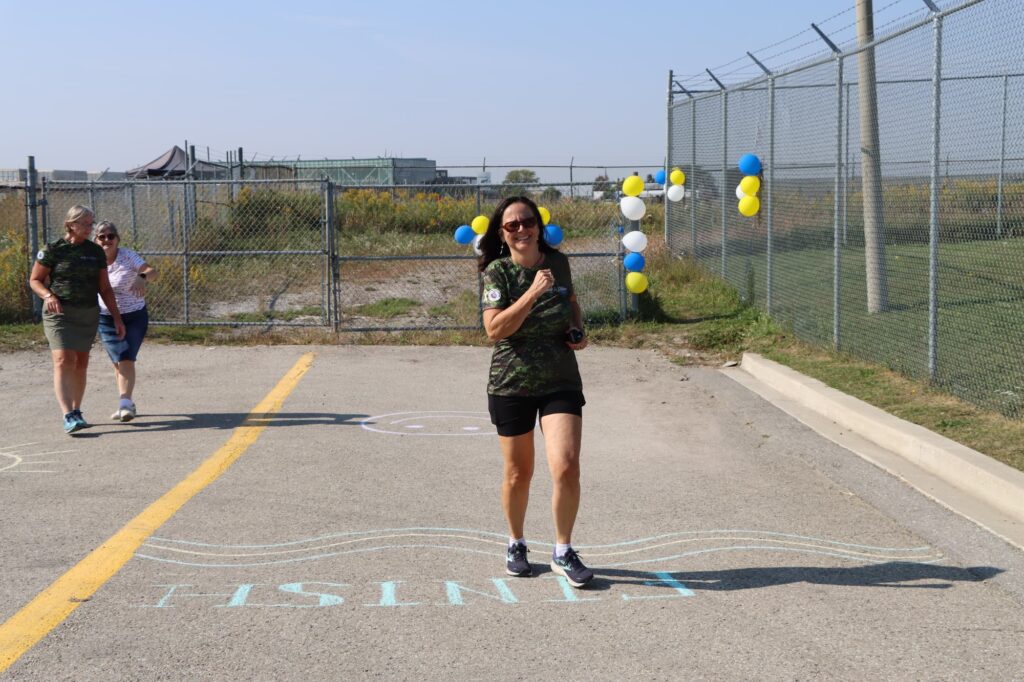A woman runs across a chalk finish line. | Une femme franchit une ligne d’arrivée tracée à la craie.